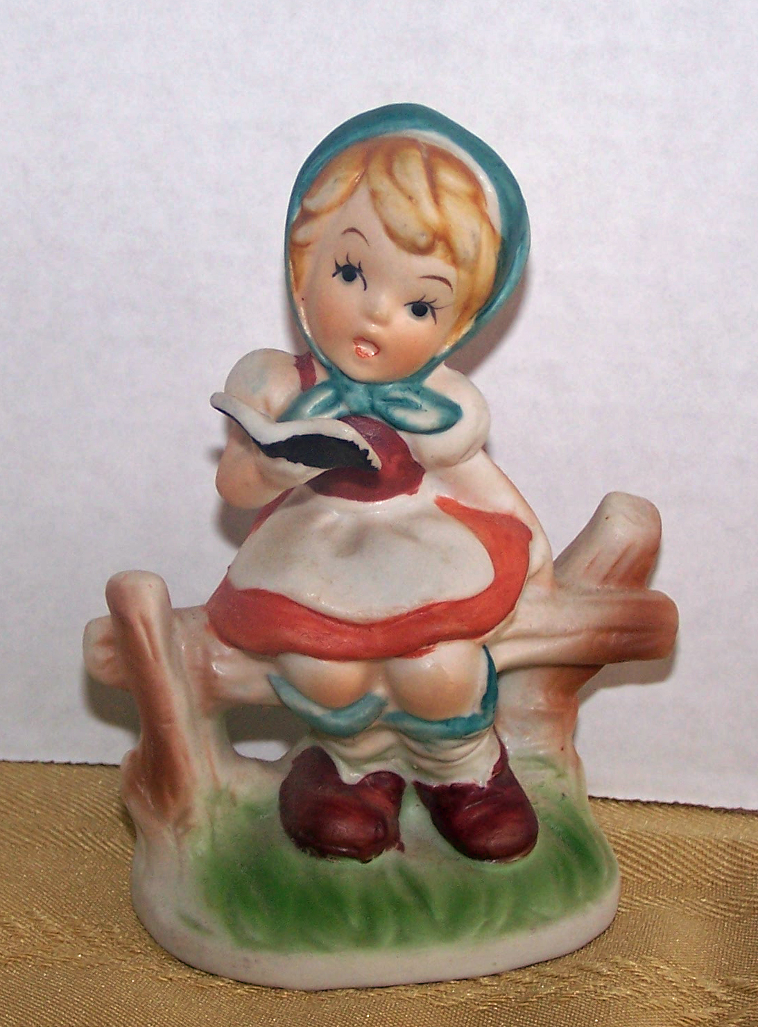 Bisque Girl Sitting on Fence, Holding a Book