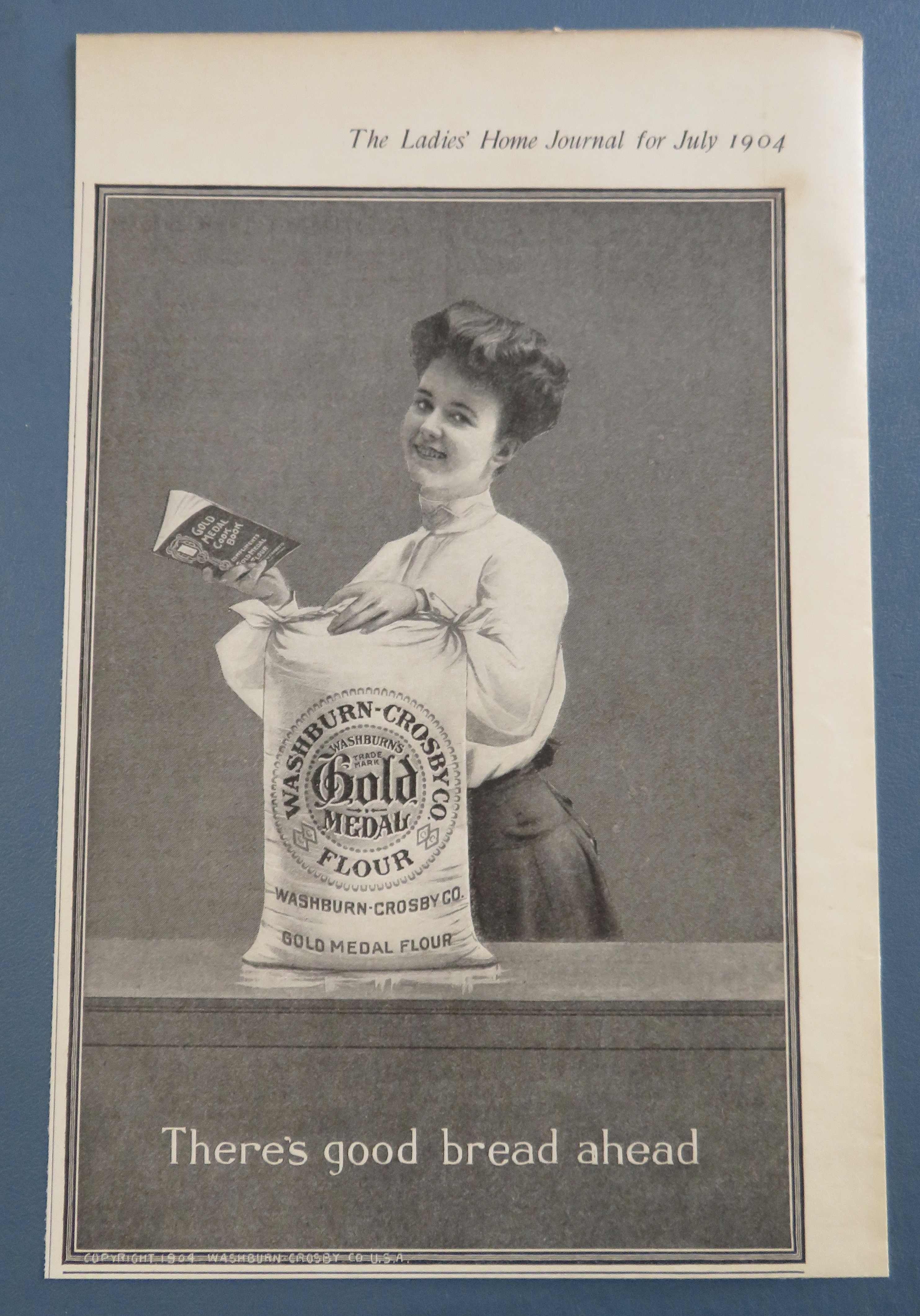 1904 Gold Medal Flour with Woman Holding Cook Book