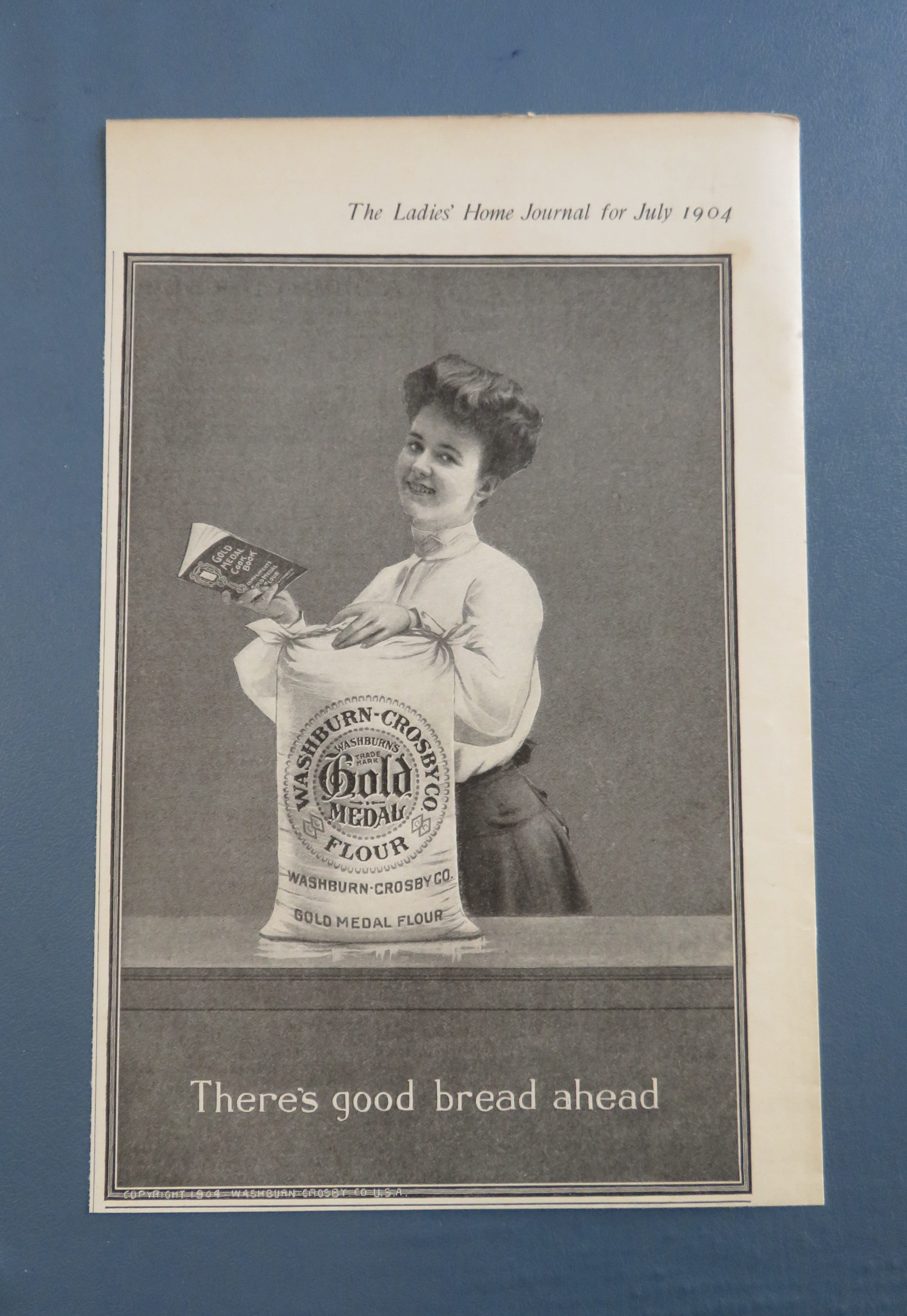 1904 Gold Medal Flour with Woman Holding Cook Book