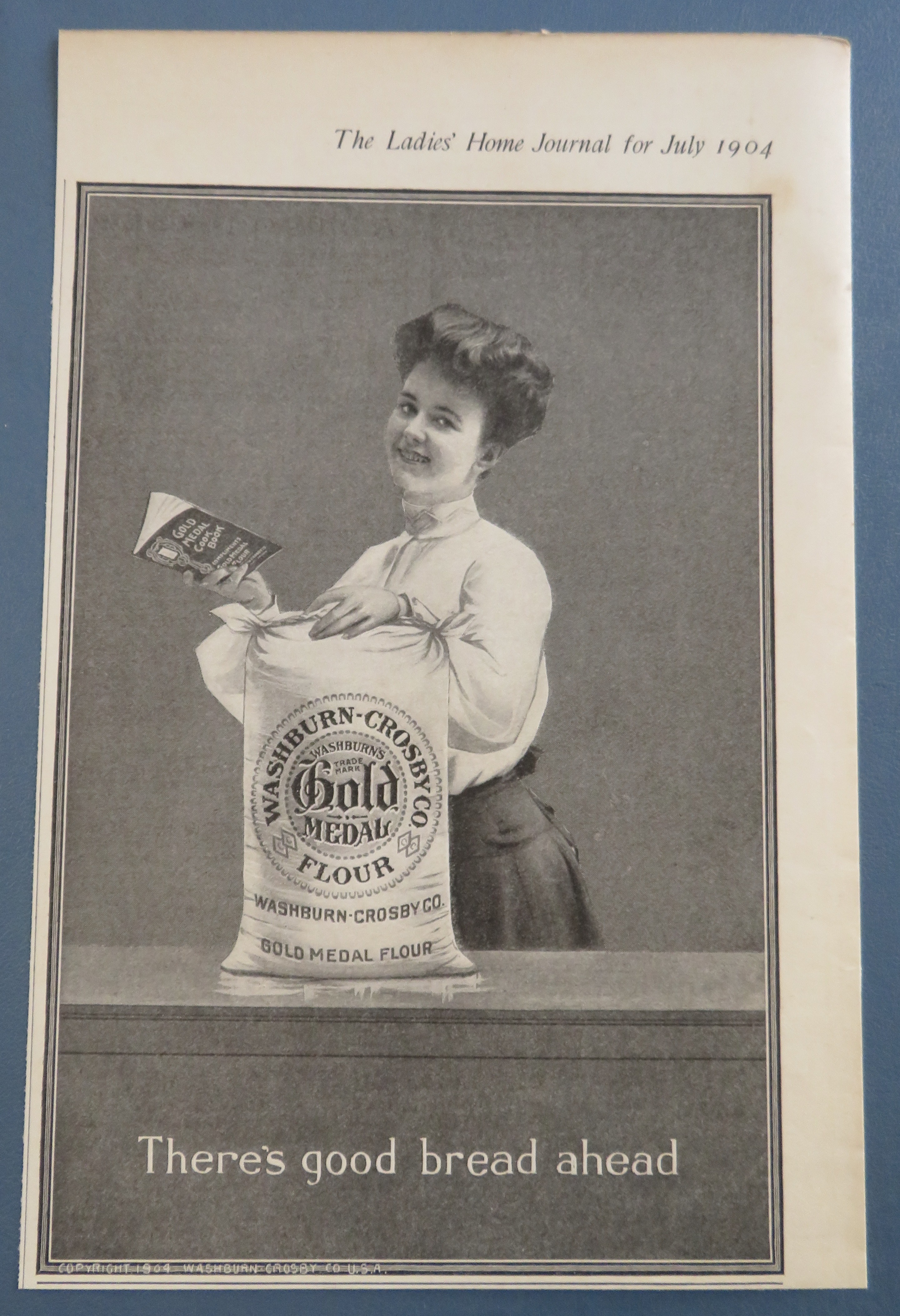 1904 Gold Medal Flour with Woman Holding Cook Book