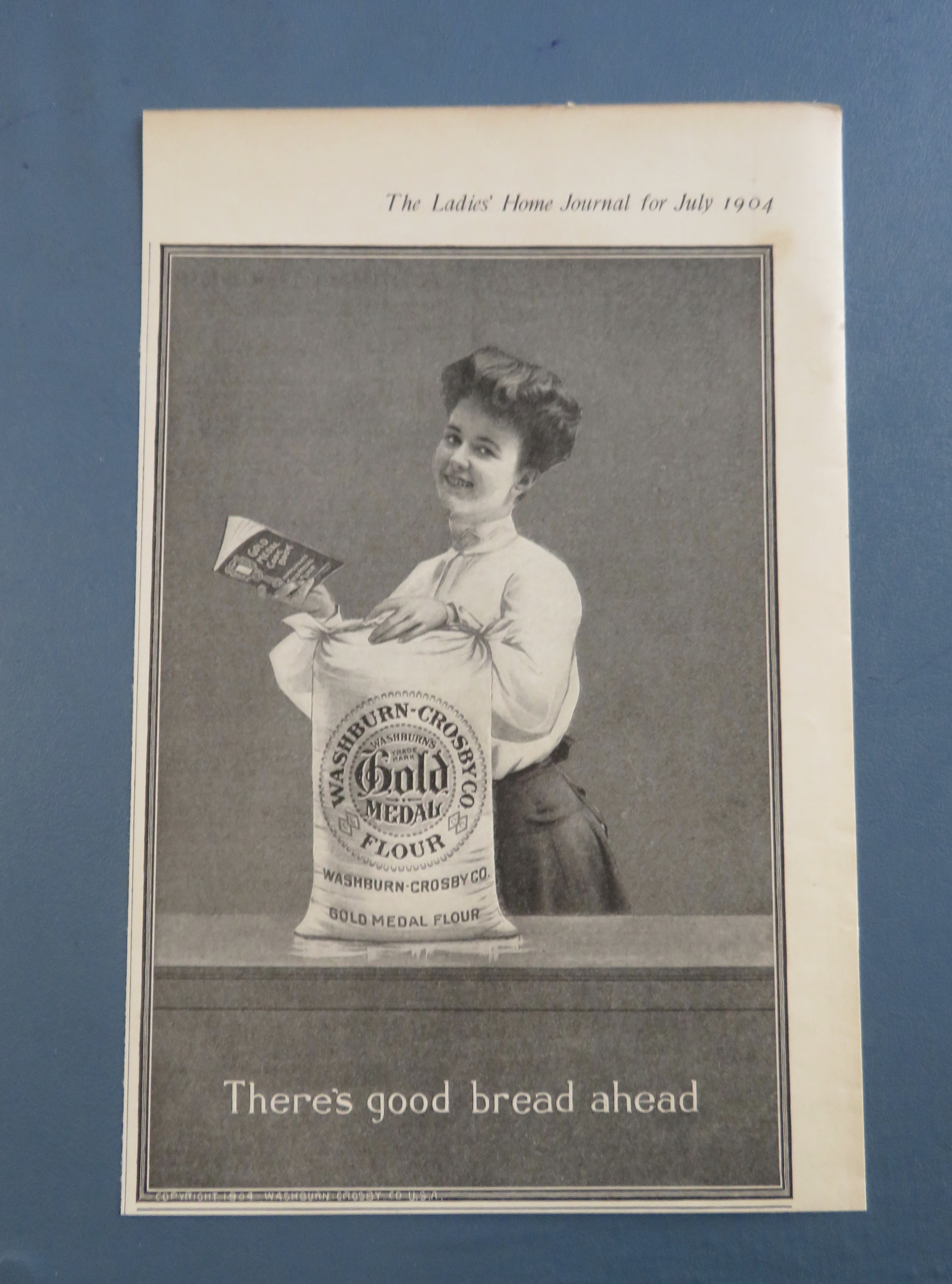 1904 Gold Medal Flour with Woman Holding Cook Book