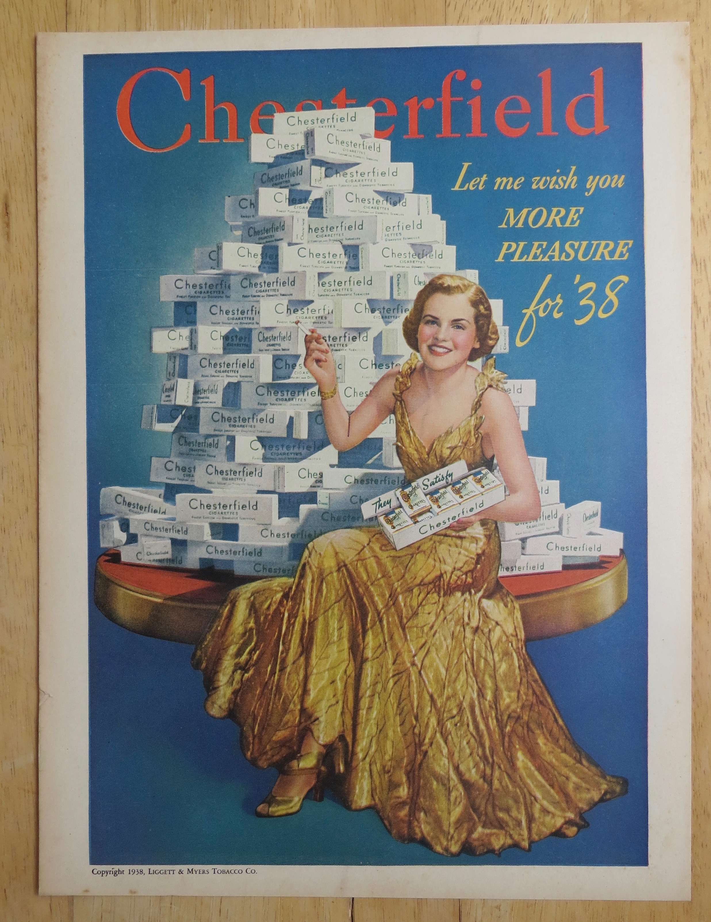 1938 Chesterfield Cigarettes w/Woman Sitting By Stack